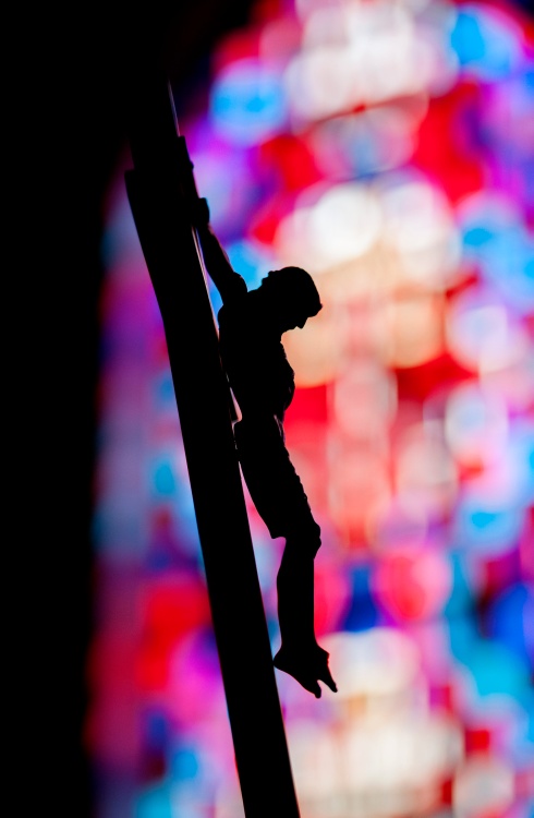 Crucifix is seen silhouetted against stained-glass window in chapel at New York correctional facility